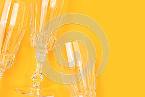 Empty crystal glasses on a yellow background.