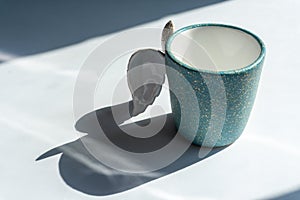 An empty cup for coffee or tea on the white background with shadows