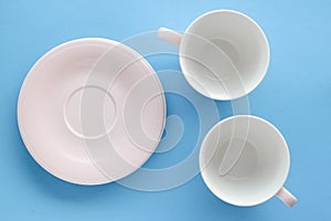 Empty cup and saucer on blue background, flatlay