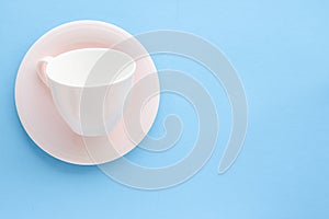 Empty cup and saucer on blue background, flatlay