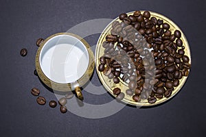 Empty cup, saucer, coffee beans on a black background