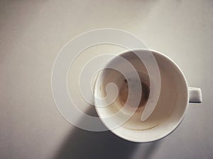 Empty cup with stain of hot coffee on white table background.