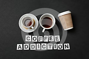 Almost empty cups of coffee with text COFFEE ADDICTION on dark background