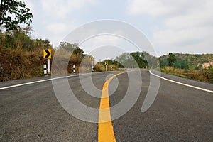 Empty curve road in the country and have forest on the street. Traffic sign warning curve