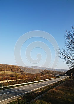 Empty curved road,blue sky and sun