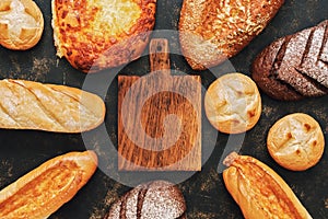 An empty cutting board and a frame made from a variety of bread. View from above. Copy space.