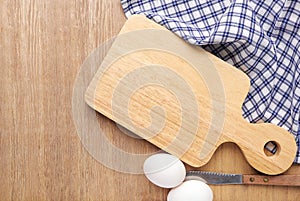 Empty cutting board ,napkins, white eggs and knife on wooden table.