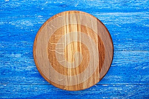 Empty cutting board in a round shape on a blue wooden table. Space for text