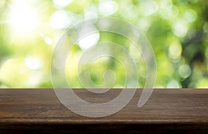 Empty dark brown hard wood table top with sun and blur green tree bokeh background, Template mock up for montage of product