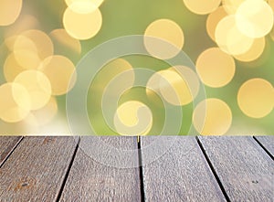 empty dark brown wooden table top with blurred yellow gold round lights bokeh on green background