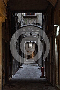 An empty dark narrow alley with a lonely figure in the distance in the city of Venice, Italy