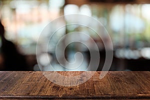 Empty dark wooden table in front of abstract blurred bokeh background of restaurant.