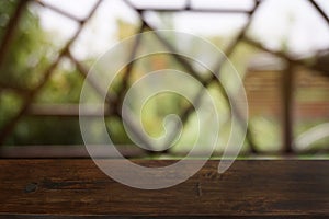 Empty dark wooden table in front of abstract blurred bokeh background of restaurant.