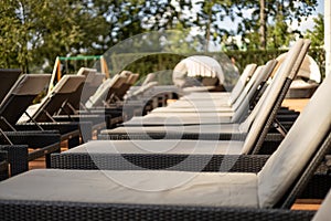 Empty deck chair near outdoor swimming pool in hotel resort for leisure vacation. Empty wooden deck chair with a soft