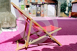Empty deck chair on pink surface