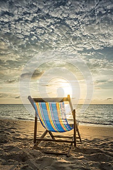 Empty deck chair at secluded beach during sunset