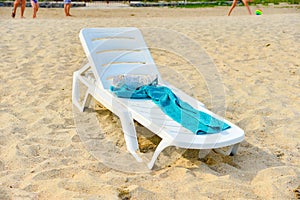 An empty deck chair with a towel stands on the beach by the sea