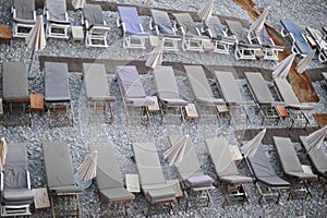 Empty deck chairs with mattresses and umbrellas on a pebble beach on Mediterranean sea coast in summer