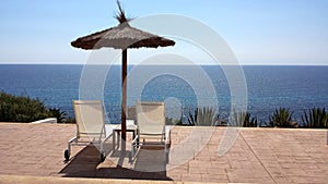 Empty deck chairs under the umbrella above the water.