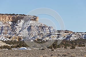 Empty desert landscape with snow covered rocky mountain on clear blue day