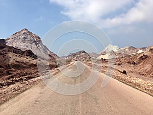 Empty desert road view with dreamy multicoloured mountains in Hormuz Island, Iran. Middle East roadtrip inspiration