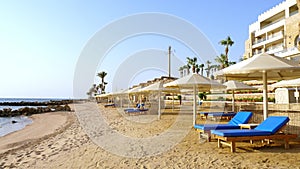 Empty, deserted beach with palm trees, sun loungers and umbrellas of an expensive hotel, during or after a lockdown due