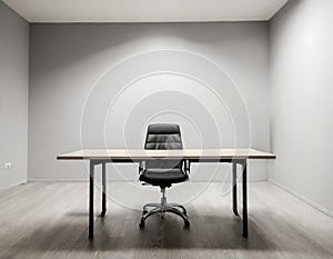 Empty desk in small office room with grey walls