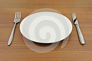 Empty dish, knife and fork on wood table