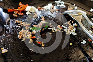 An empty dish of stir-fry minced meat with chilies and basil and steamed rice on a black plate