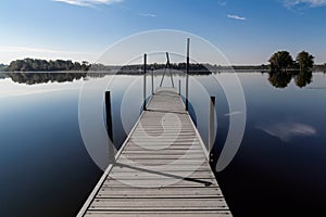 An empty dock on a lake with trees in background.