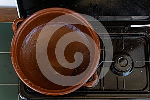 Empty earthenware casserole on an unlit gas stove