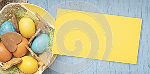 Empty Easter yellow card, colored eggs on a backdrop