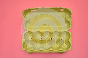 Empty egg packaging in a cardboard box on a pink background