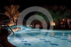 Empty enlightened swimming pool in a hotel resort during hot summer night