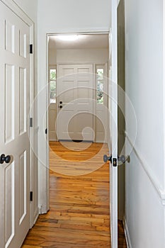 The empty entrance of a newly renovated and painted white house with hardwood floors and a wide front door