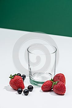 Empty even glass with fresh strawberries nearby