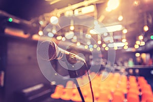 Empty event hall: Close up of microphone stand, empty seats in the blurry background