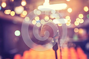 Empty event hall: Close up of microphone stand, empty seats in the blurry background