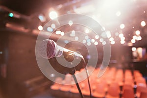 Empty event hall: Close up of microphone stand, empty seats in the blurry background