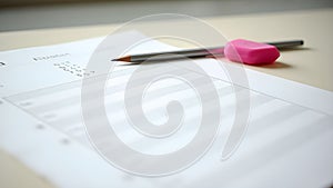 Empty exam desk with multiple-choice answer sheet, sharpened pencil, and eraser