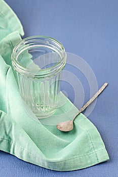 An empty faceted jar and a vintage spoon on a blue background