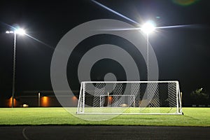 Empty, floodlit soccer field at night.