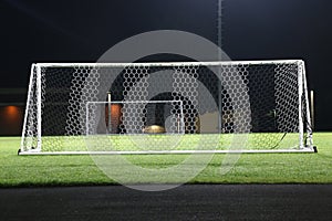 Empty, floodlit soccer field at night.