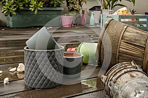 Empty flower pots of all kinds next to various plants on the wooden floor with rusty metal flower pots in the foreground