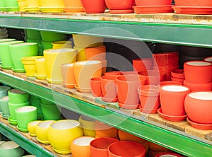 Empty flower pots in a store or greenhouse. Ceramic or plastic flower pots at the shop. Colorful flower pots on the shelf in the