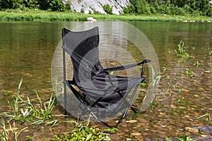 An empty folding chair stands in the water