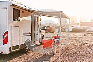 Empty folding chairs and table under canopy near recreational vehicle camper trailer