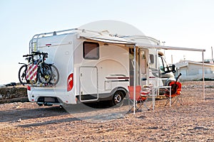 Empty folding chairs and table under canopy near recreational vehicle camper trailer photo