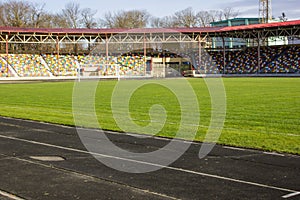 An empty football field. Soccer field grass. Graphite running road track with white marking lines near green football