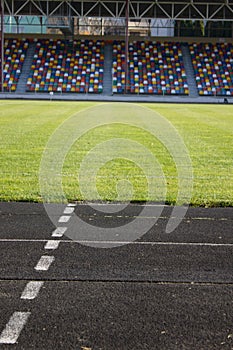 An empty football field. Soccer field grass. Graphite running road track with white marking lines near green football